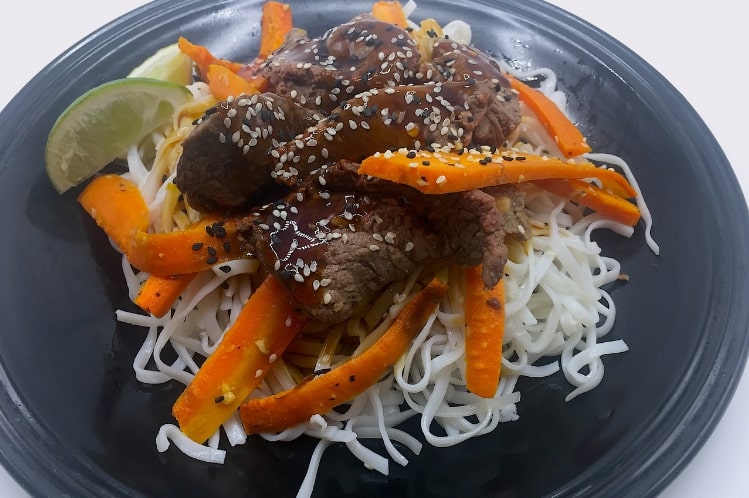 Sesame garlic beef tips served over rice noodles with ginger edamame beans.