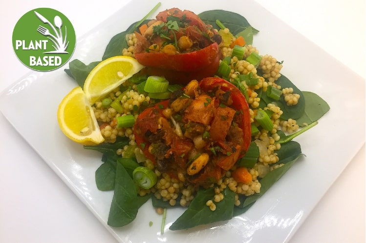 Baked bell peppers stuffed with spiced couscous pilaf, fresh vegetables and raisins.