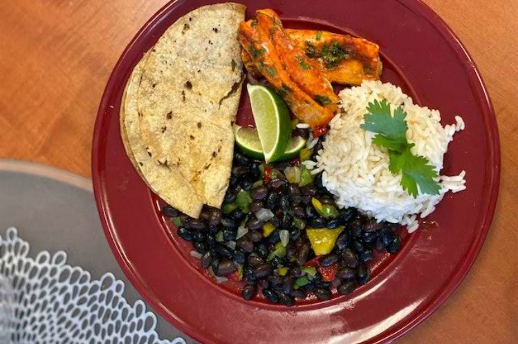 Fish taco plate with Atlantic cod, corn tortillas, lime slaw, rice and black beans.