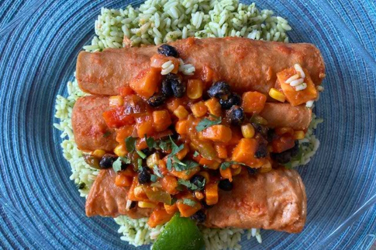 Sweet potato and black bean enchiladas topped with salsa on a bed of cilantro rice.