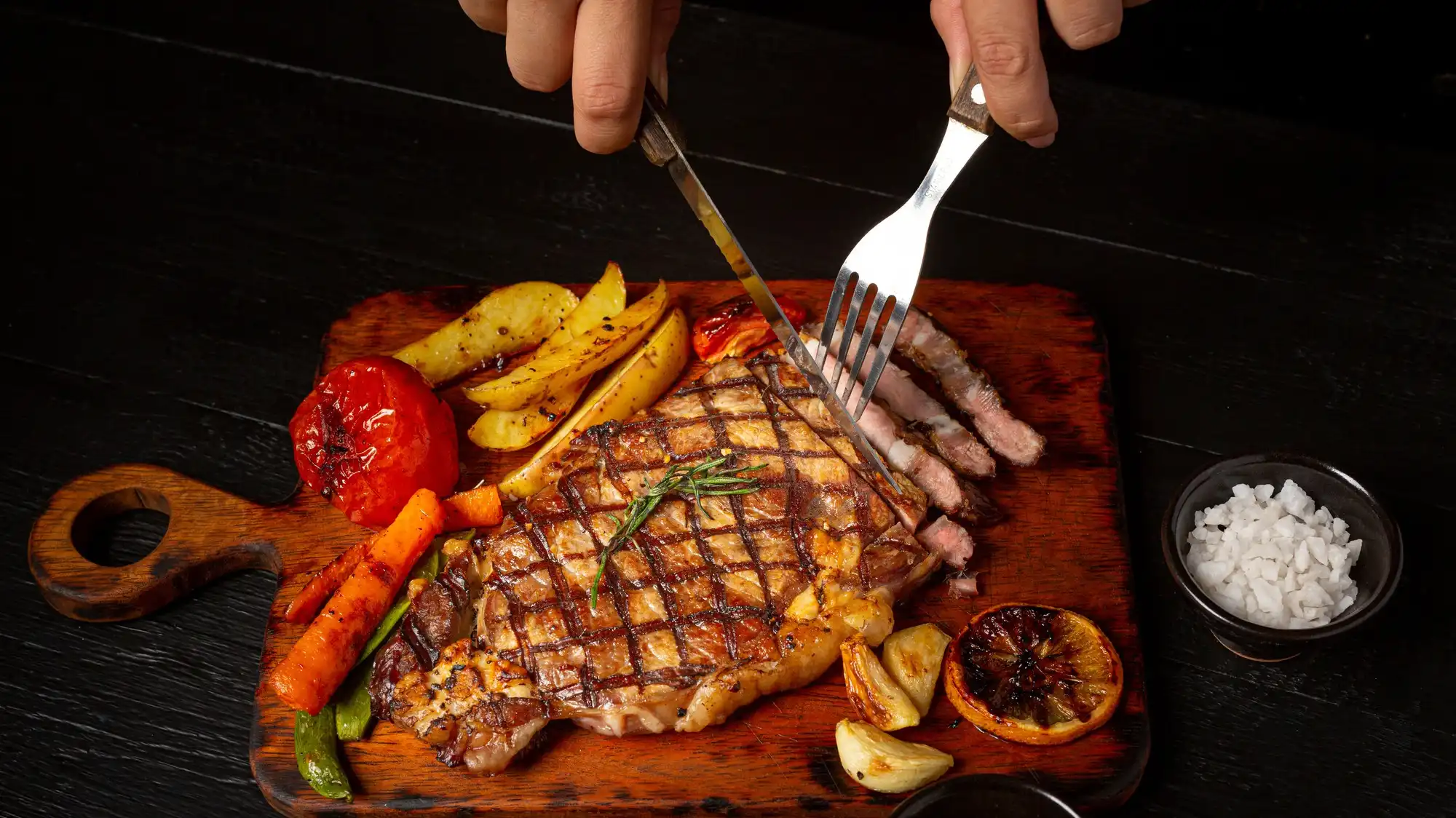 grilled-beef-steak-dinner-on-dark-wooden-board