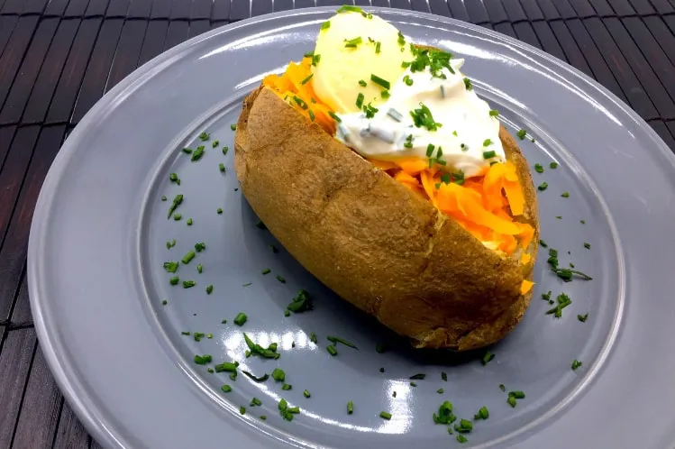 Loaded baked potato with cheddar cheese emphasizing Meal Village's pre-cooked vegetarian meal delivery services