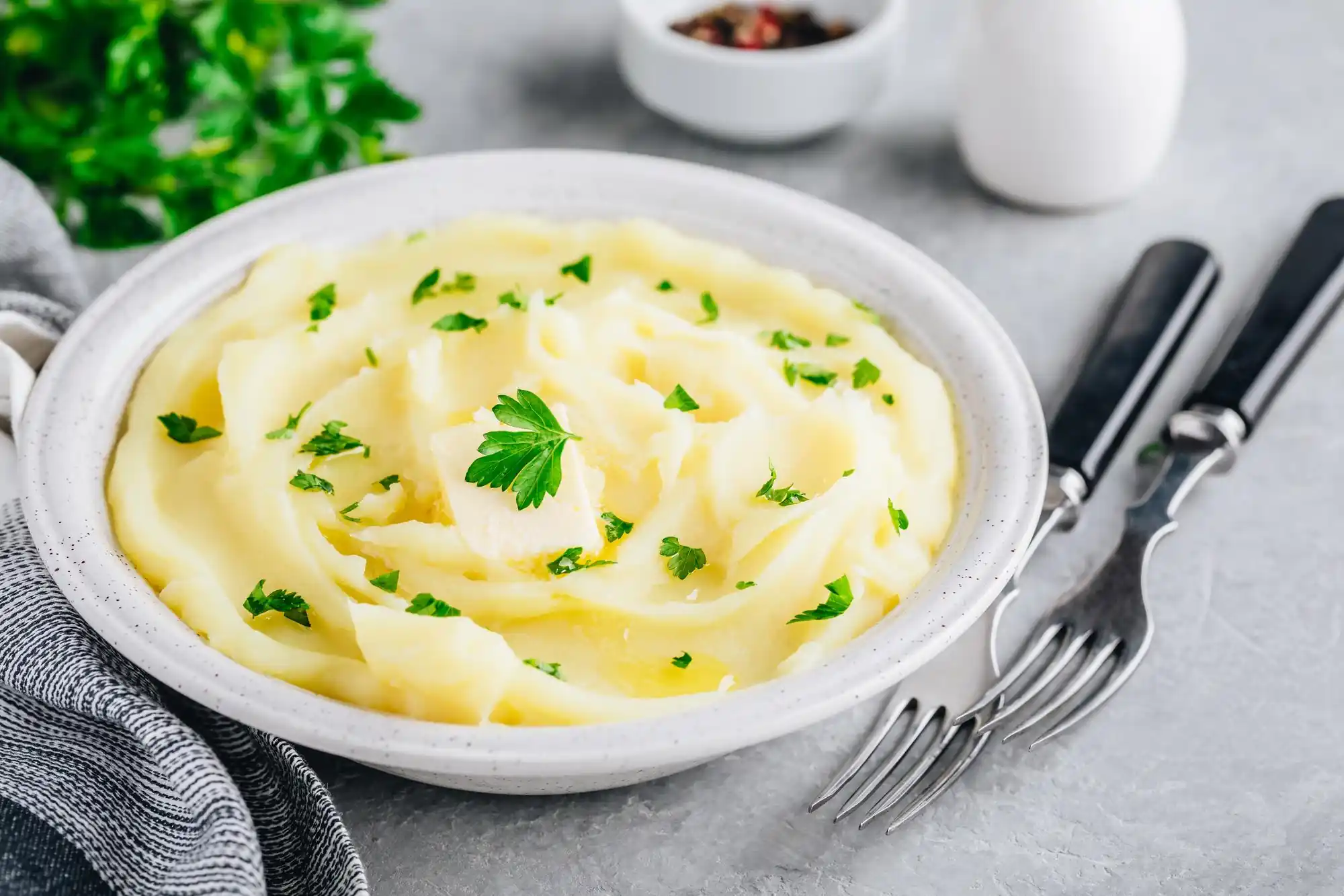 Close-up of a bowl of creamy mashed potatoes garnished with fresh parsley