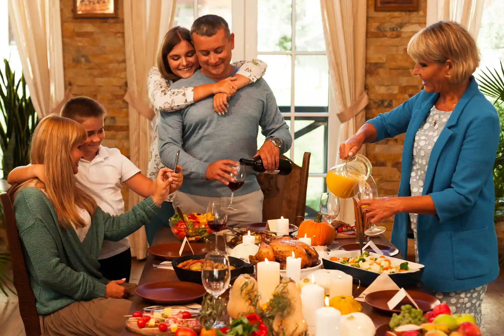 senior man standing at a dining table where the family is seated, enjoying a home-cooked meal