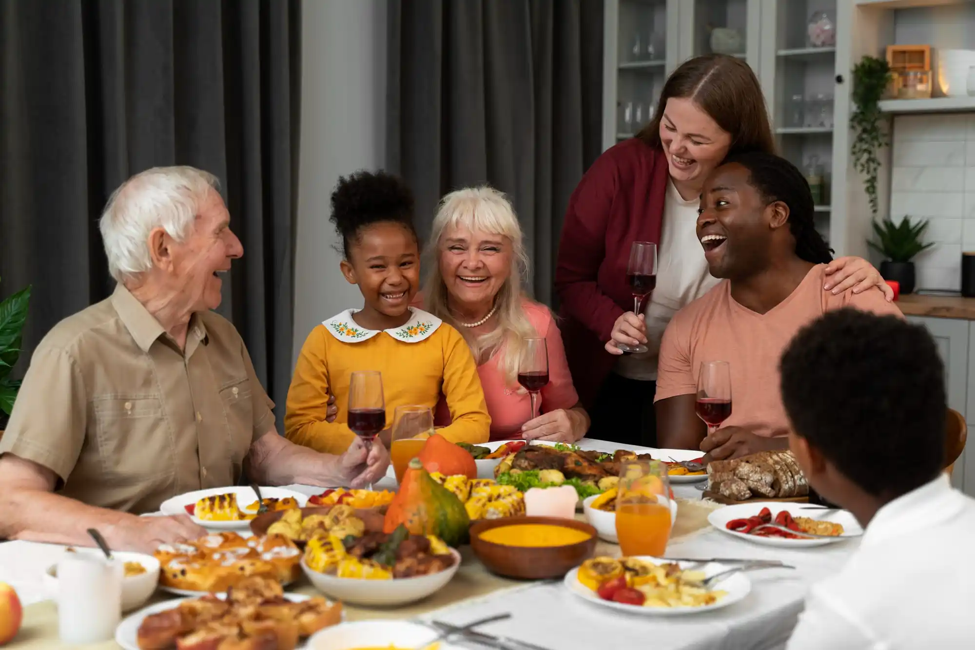 Multi-generational family gathered around a Thanksgiving dinner table, smiling and raising glasses while enjoying the holiday meal together